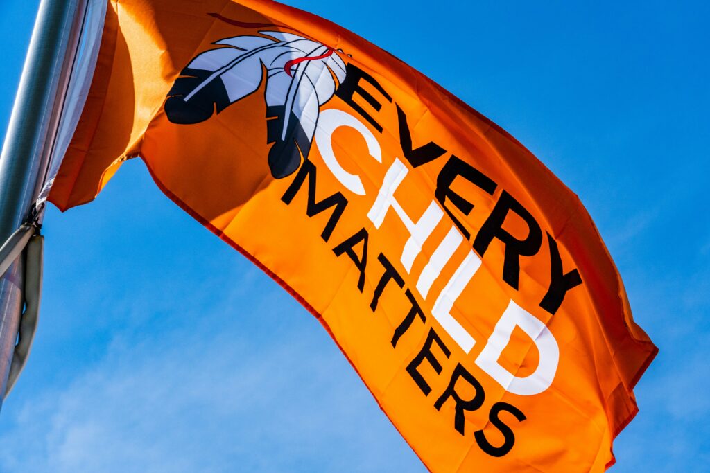 An orange flag with the text "Every Child Matters" on it